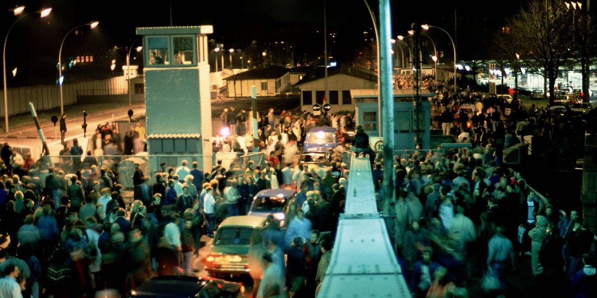 Historisches Foto von Menschen und Autos, die sich am Grenzübergang Bornholmer Straße in Berlin drängen.